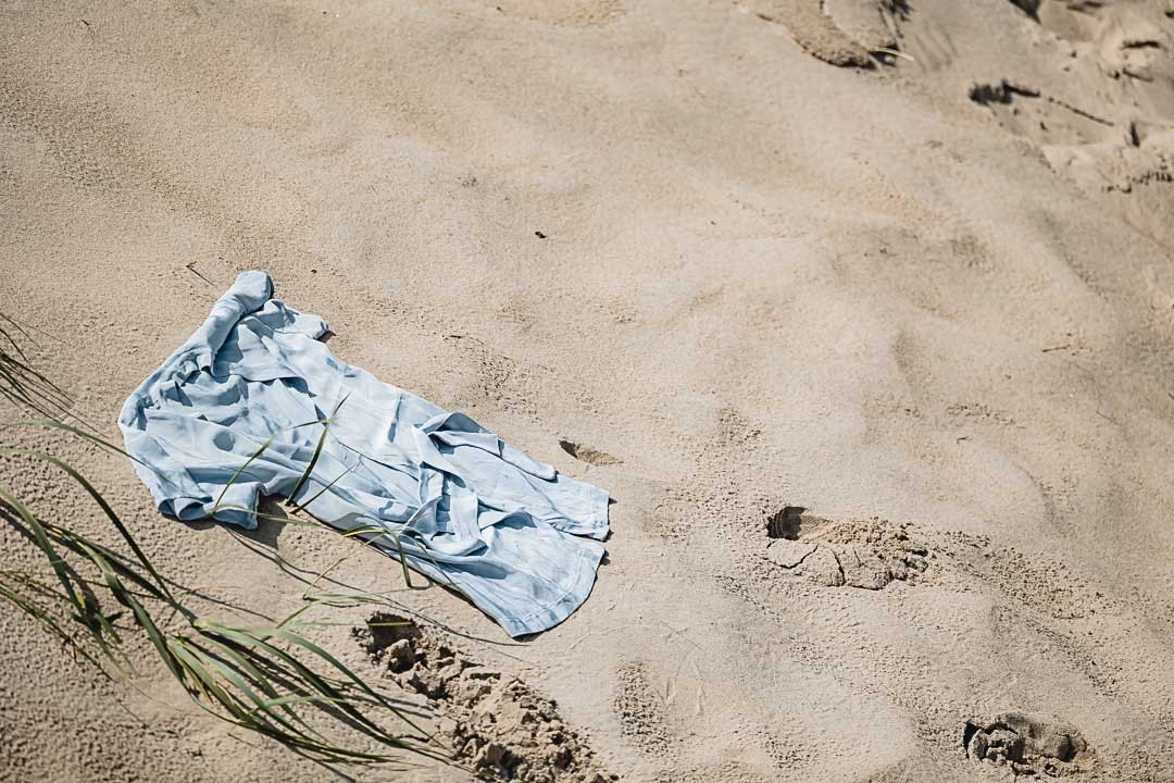 Lyseblåt plantefarvet silketørklæde bredt ud i sandet mellem klittens marehalm